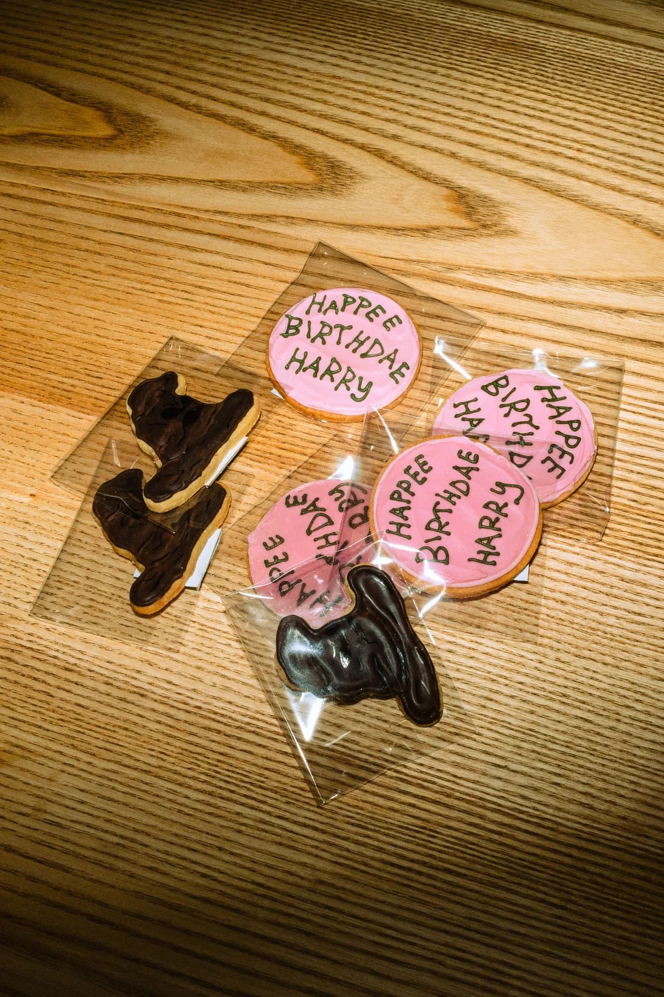 Zabalené sušenky s nápisem Happee Birthdae Harry a čokoládové žabky na dřevěném stole